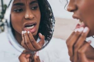 woman examines her teeth in mirror